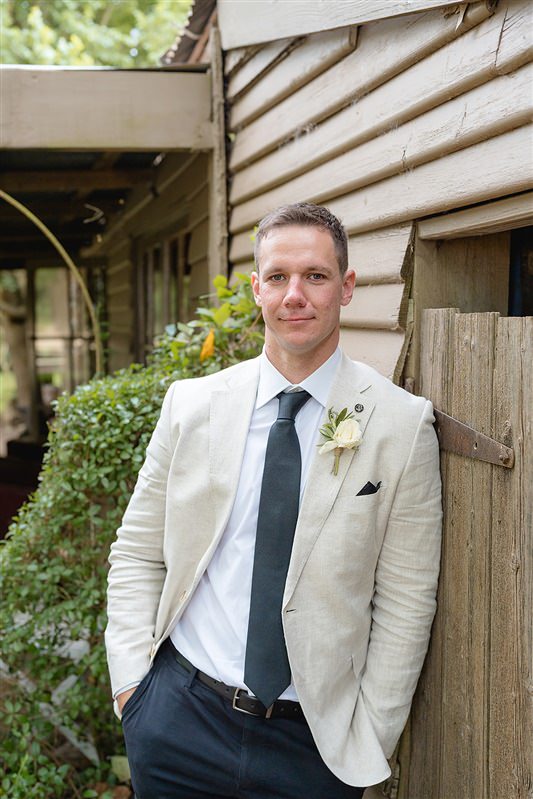 Portrait of groom standing alone in linen jacket before ceremony