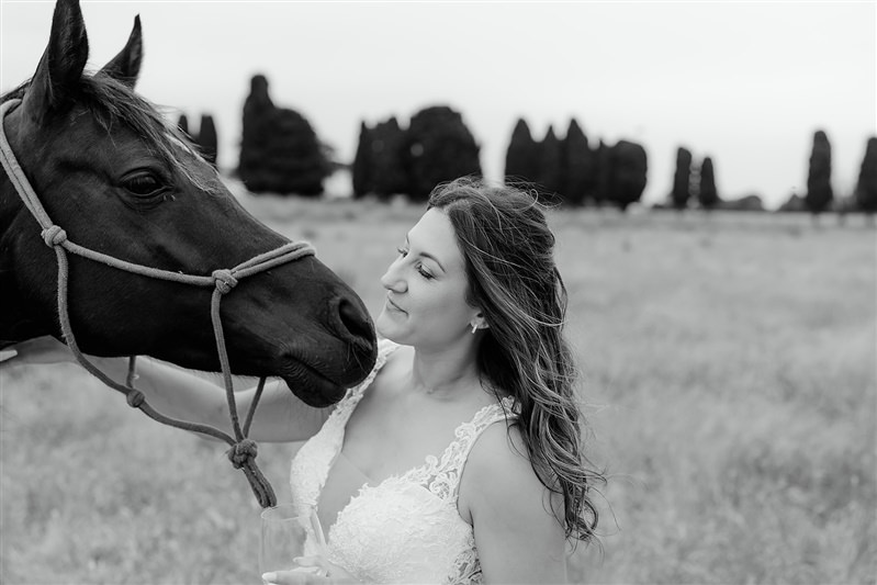 Bride smiling beside horse in soft black and white portrait