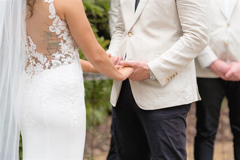 Close-up of couple holding hands with lace and blazer detail