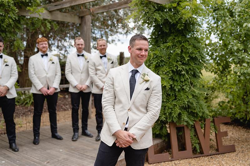 Groom smiling with hands in pockets during wedding ceremony