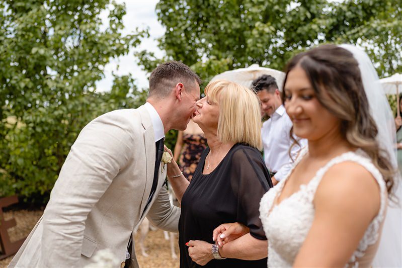 Groom kissing mother -in-law during ceremony