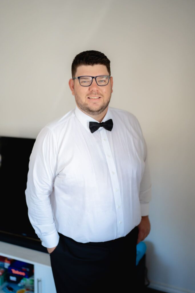  Groom getting ready in white shirt and bow tie before Witchmount Estate wedding