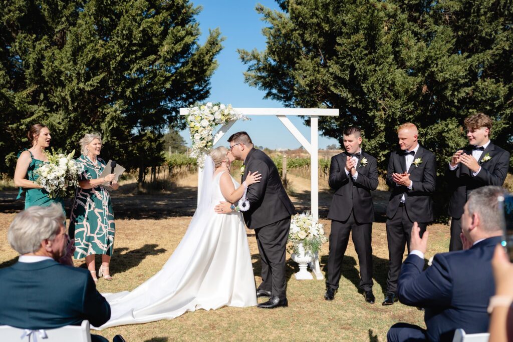Bride and groom sharing their first kiss at the altar during Witchmount Estate wedding ceremony
