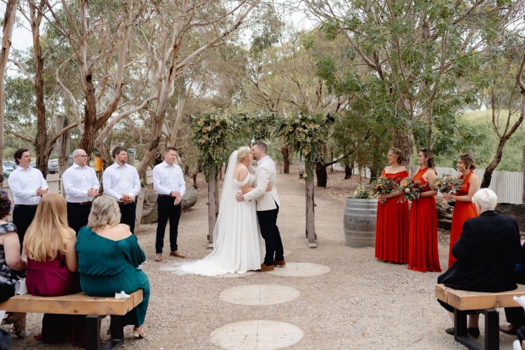 Bride and groom sharing their first kiss at Oneday Estate wedding ceremony