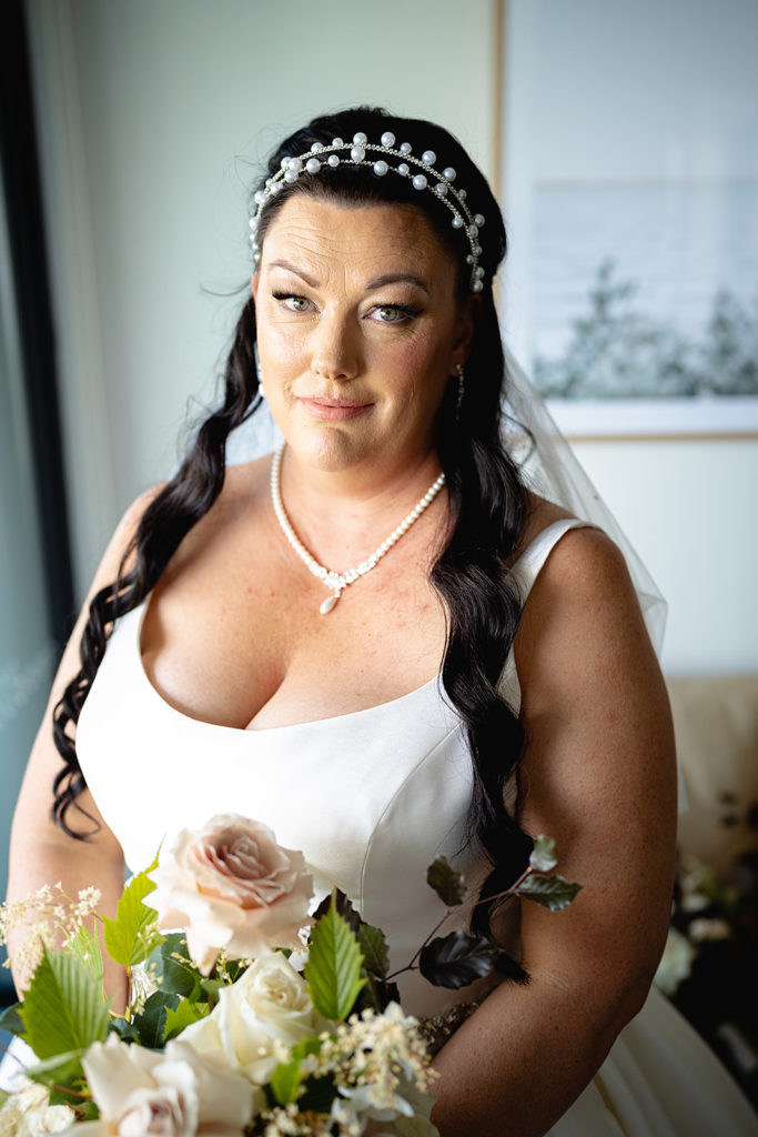 Bride standing by a window before her wedding at the Batesford Hotel.