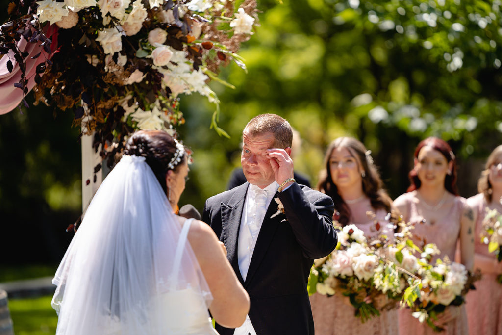 Groom wipes his tears away during the wedding ceremony at the Batesford Hotel